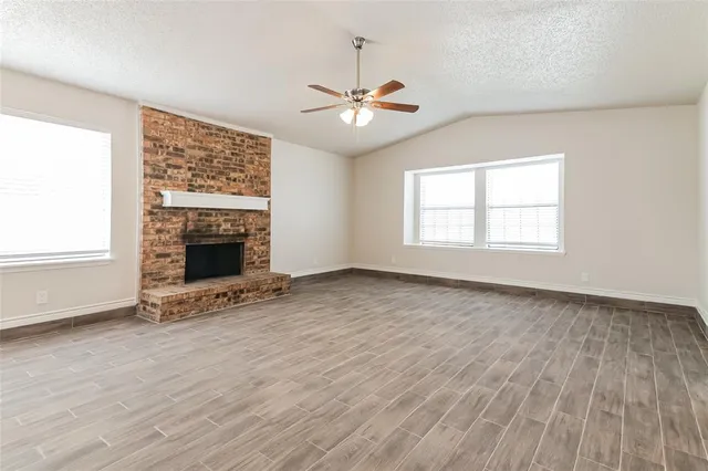 an empty room with windows fireplace and wooden floor