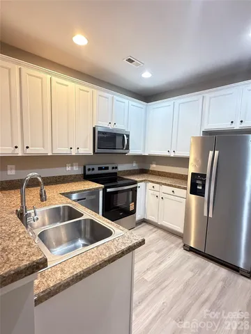 a kitchen with granite countertop a sink a counter top space stainless steel appliances and cabinets