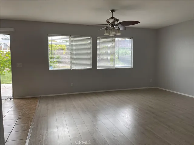 an empty room with wooden floor chandelier and windows