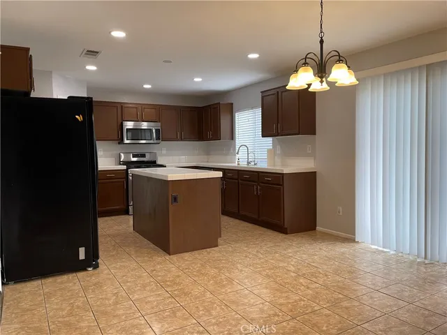 a kitchen with kitchen island granite countertop a sink a counter top space cabinets and stainless steel appliances