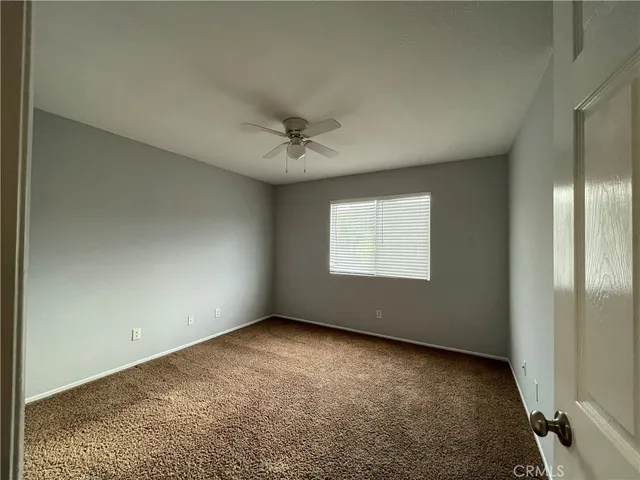 an empty room with a chandelier fan and windows