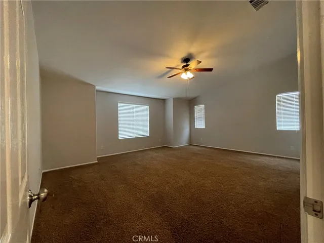 an empty room with windows and chandelier fan