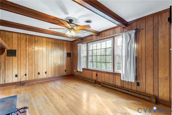 an empty room with wooden floor cabinet and windows
