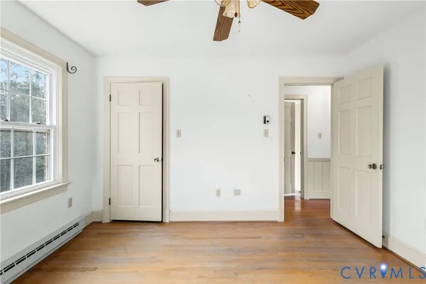 a view of empty room with wooden floor and fan