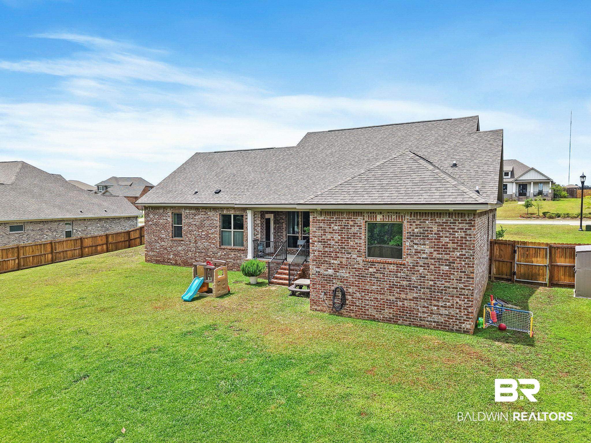 13233 Ibis Boulevard Daphne, AL 36527 - Photo 63 of 100 Expansive backyard featuring a manicured lawn, brick exterior, covered patio, and wood privacy fencing