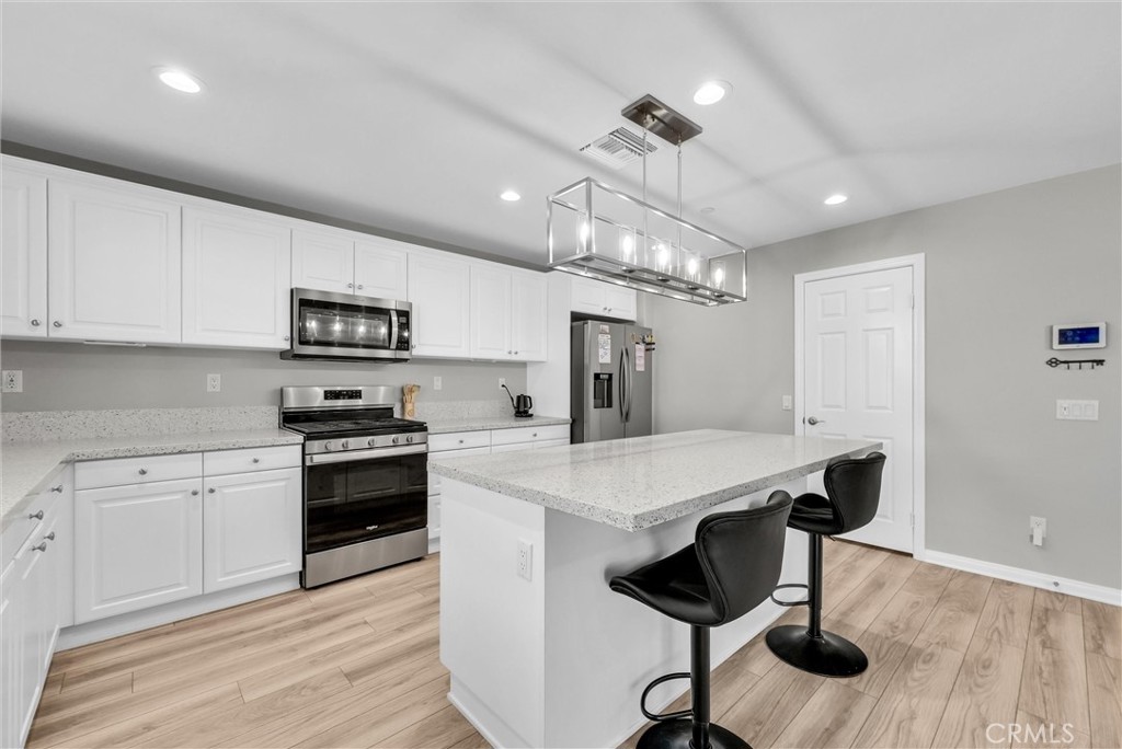 26538 San Jacinto Road Menifee, CA 92585 - Photo 10 of 34 a kitchen with stainless steel appliances kitchen island a stove a table and chairs in it