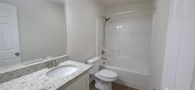 a bathroom with a granite countertop sink toilet mirror and bathtub