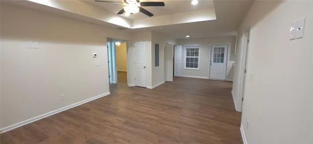 an empty room with wooden floor and a ceiling fan