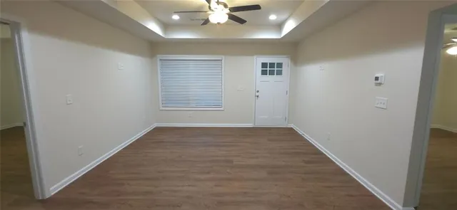 an empty room with wooden floor and fan