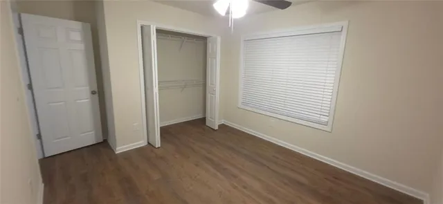 an empty room with wooden floor closet and windows