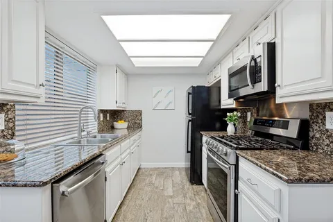 a kitchen with stainless steel appliances granite countertop a sink stove and refrigerator