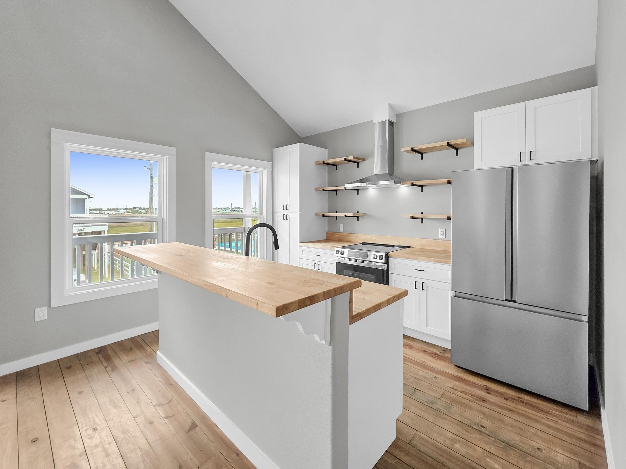 1041 Sunset Circle Crystal Beach, TX 77650 - Photo 16 of 45 a kitchen with stainless steel appliances granite countertop a refrigerator a sink dishwasher a stove with wooden floors and a large window