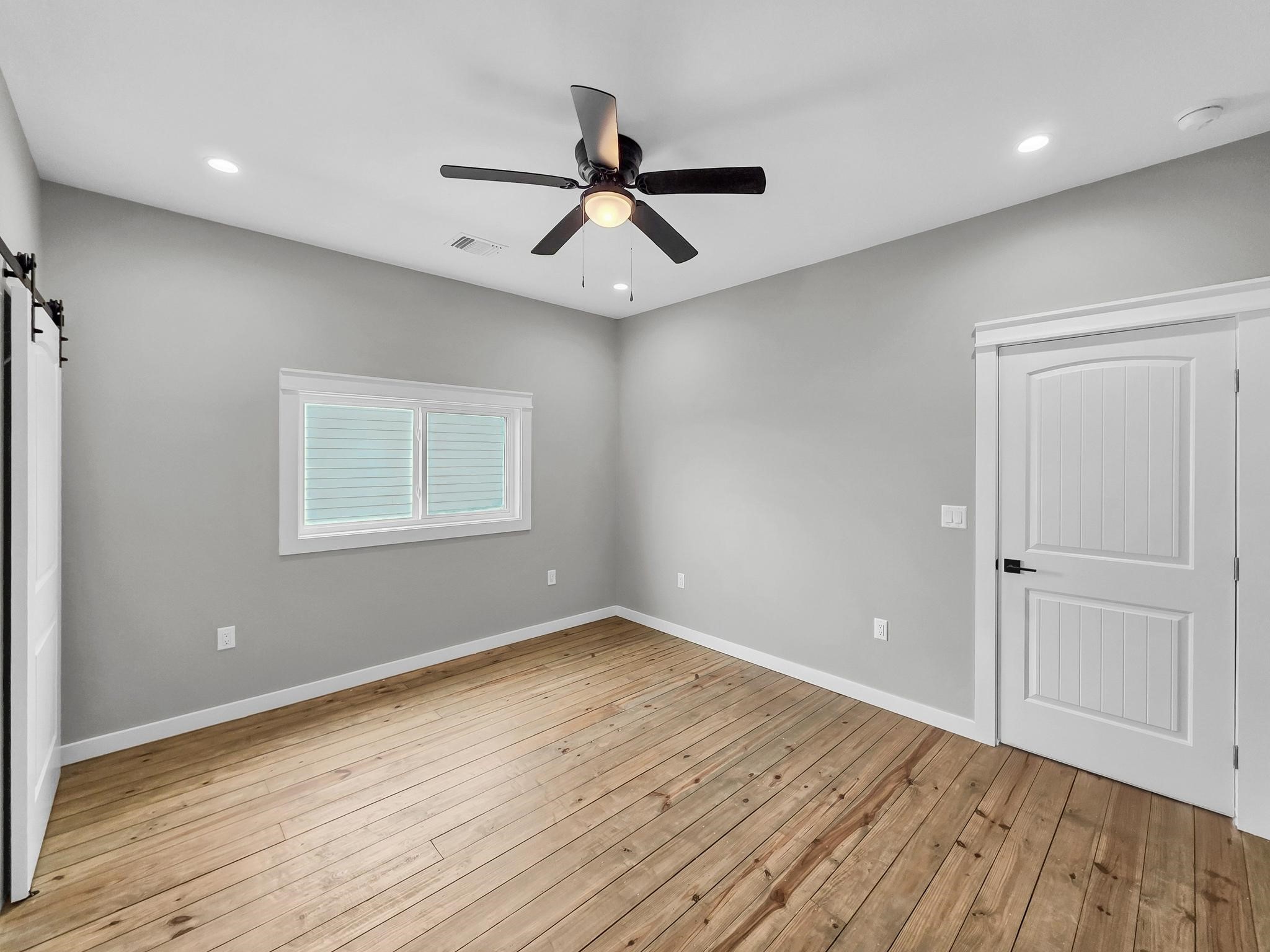 1041 Sunset Circle Crystal Beach, TX 77650 - Photo 32 of 45 an empty room with wooden floor ceiling fan and windows