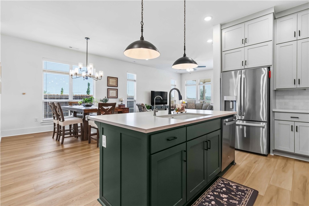 450 Fox Trail Springdale, AR 72762 - Photo 6 of 38 Modern kitchen featuring a dark green island with integrated sink, white countertops, and light wood-finish flooring