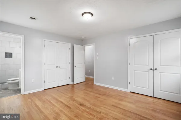 a view of an empty room with wooden floor and a toilet