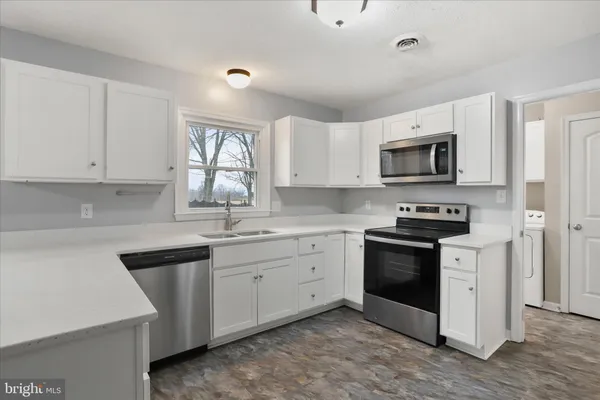 a kitchen with stainless steel appliances granite countertop a stove a sink and a microwave