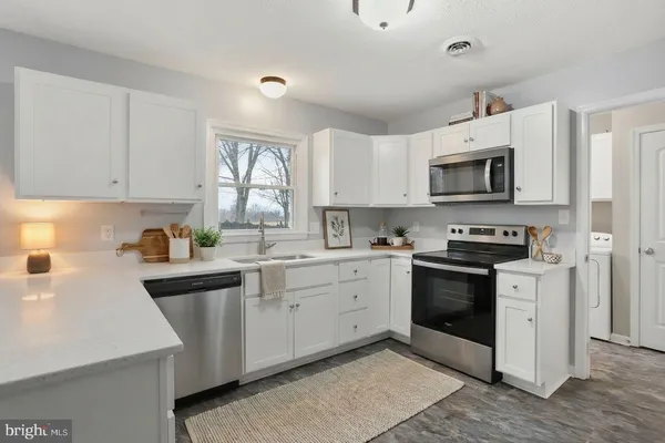 a kitchen with granite countertop a sink cabinets and stainless steel appliances