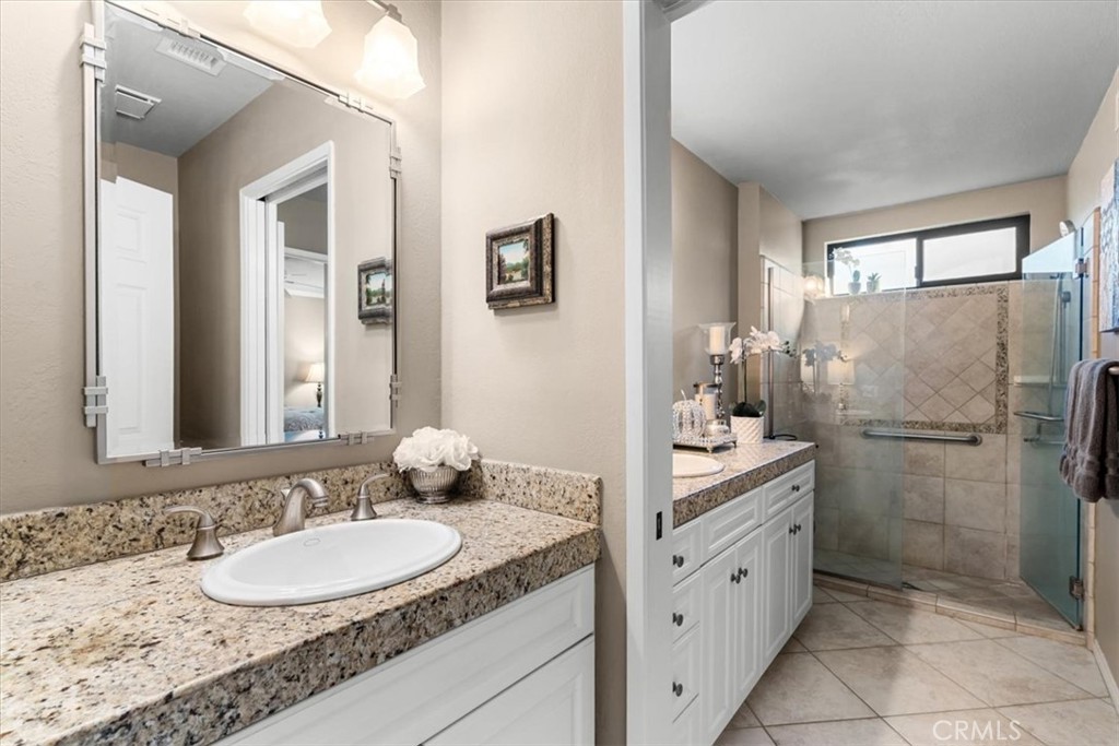 393 Gran Via Palm Desert, CA 92260 - Photo 26 of 60 a bathroom with a granite countertop sink a mirror and a shower