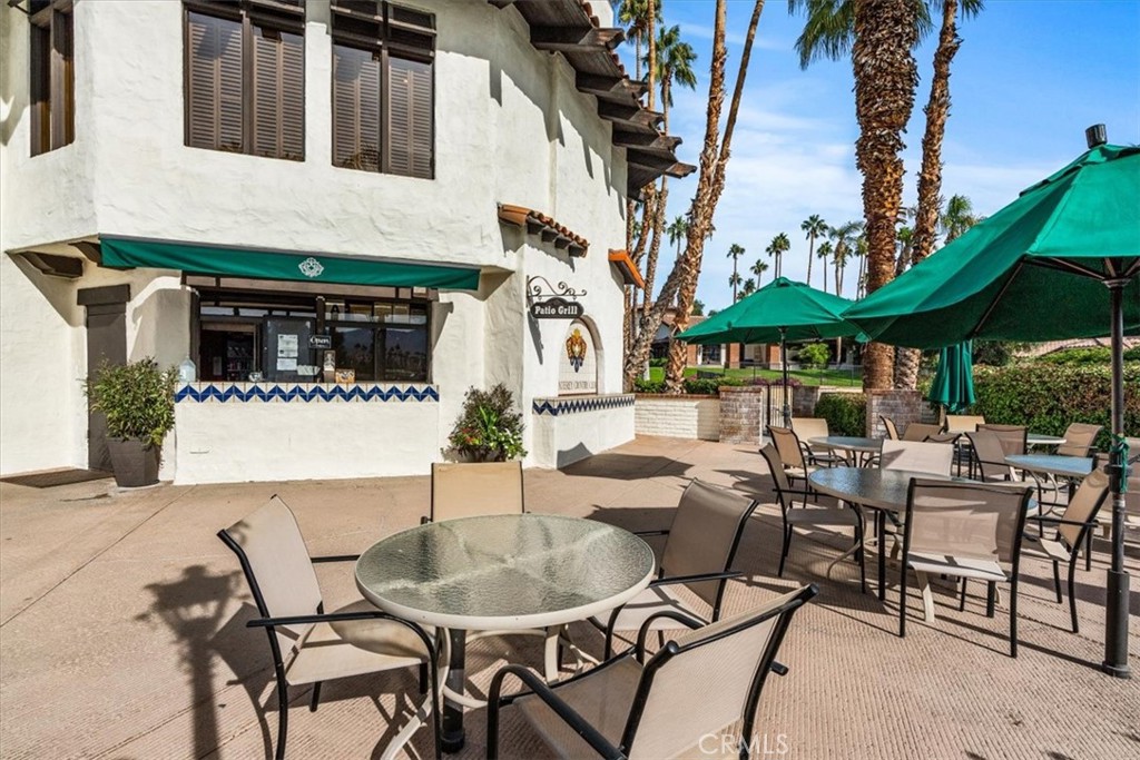 393 Gran Via Palm Desert, CA 92260 - Photo 56 of 60 a view of a patio with table and chairs under an umbrella with a fire pit and a fire pit