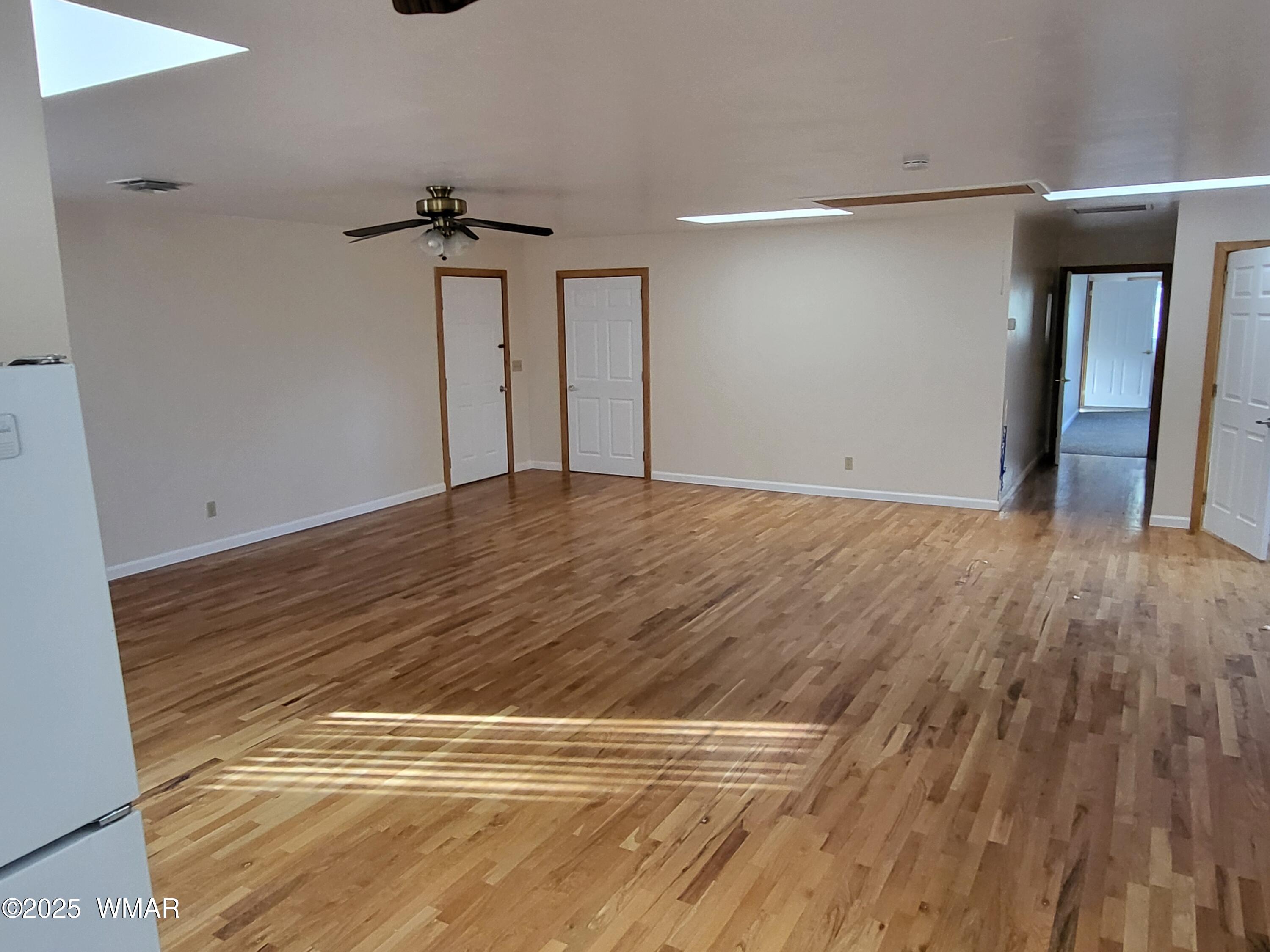 2052 Lone Mountain Road Overgaard, AZ 85933 - Photo 19 of 24 a view of a livingroom with wooden floor and a ceiling fan