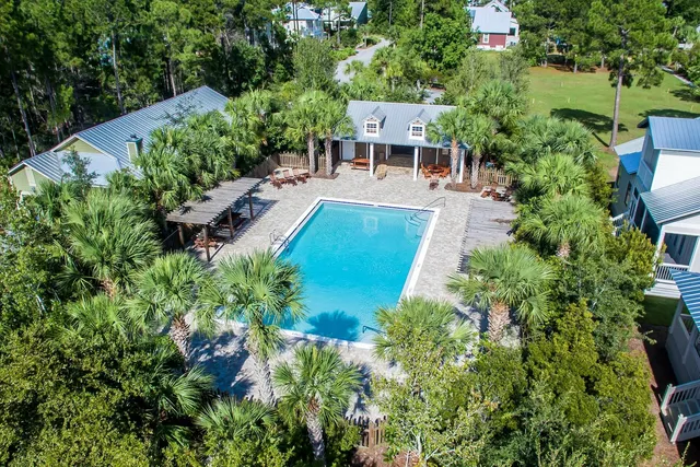 an aerial view of a house with a yard and trees all around