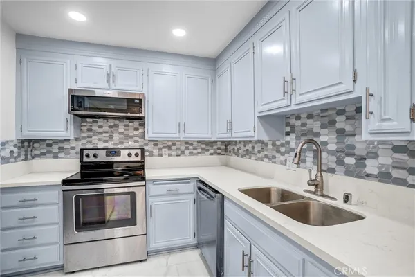 a kitchen with white cabinets a sink and appliances