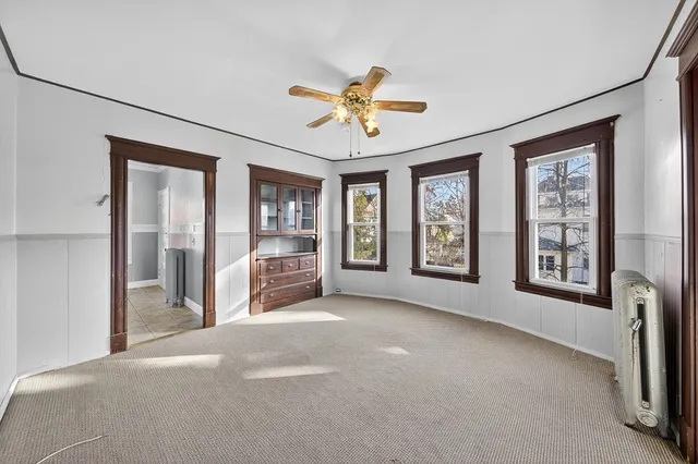 a view of an empty room with a window and a kitchen