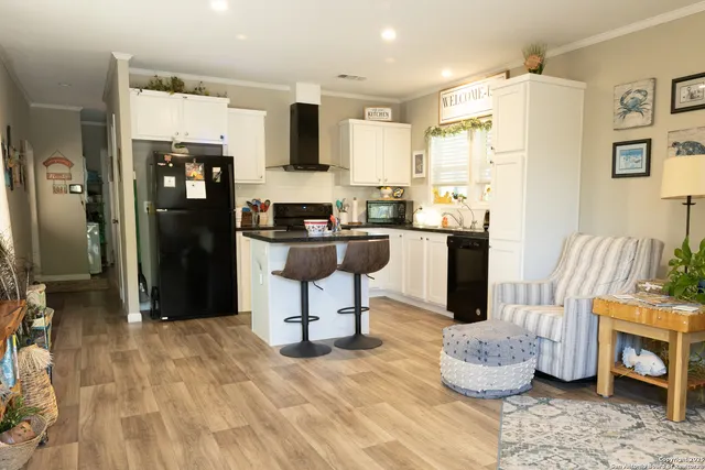 a kitchen with stainless steel appliances kitchen island granite countertop a refrigerator a stove a oven with white cabinets and wooden floor