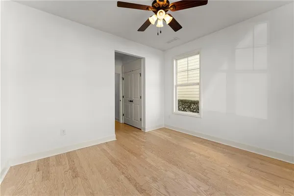 an empty room with wooden floor fan and windows