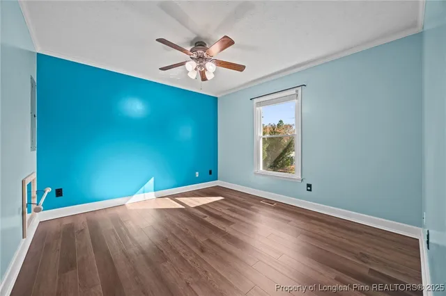 a view of an empty room with window and wooden floor