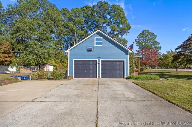 a view of a house with a yard and large tree