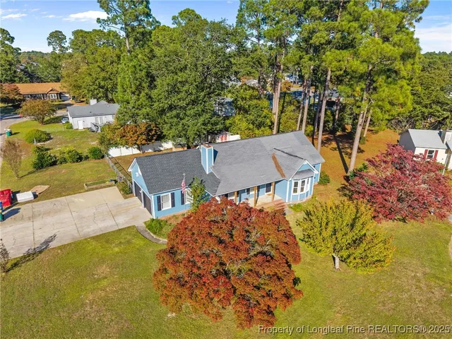 an aerial view of a house with swimming pool and large trees