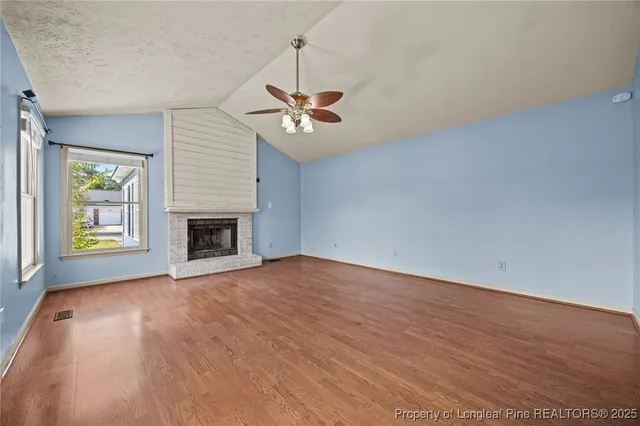 an empty room with windows and chandelier fan
