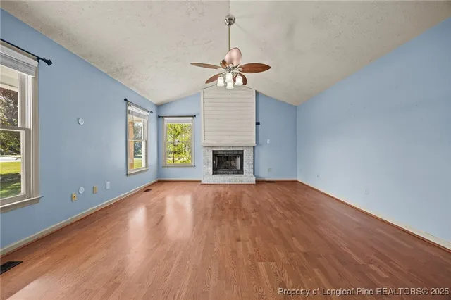 an empty room with windows and fireplace