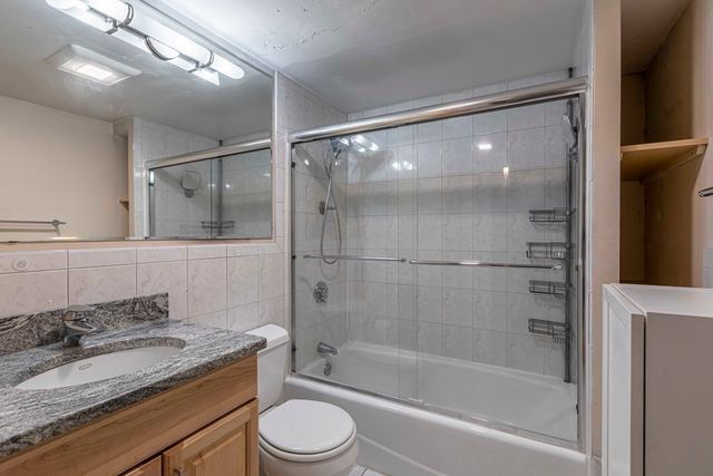 a bathroom with a granite countertop sink toilet and shower