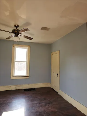 a view of an empty room with a window and wooden floor
