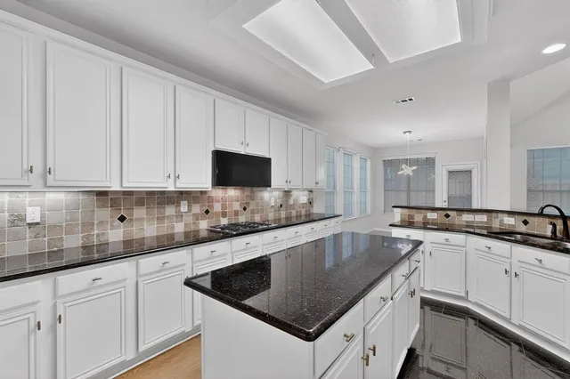 a kitchen with granite countertop white cabinets sink and stainless steel appliances