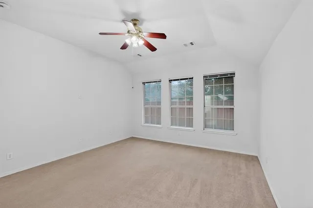 an empty room with windows and fan