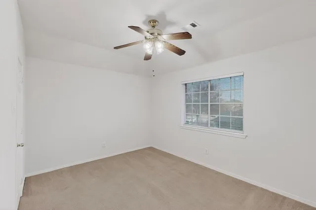 an empty room with windows and fan