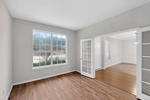 an empty room with wooden floor and windows