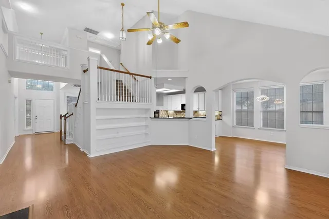 a view of an empty room and kitchen with wooden floor
