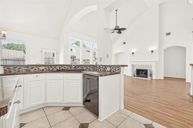 a view of an empty room with wooden floor and a ceiling fan