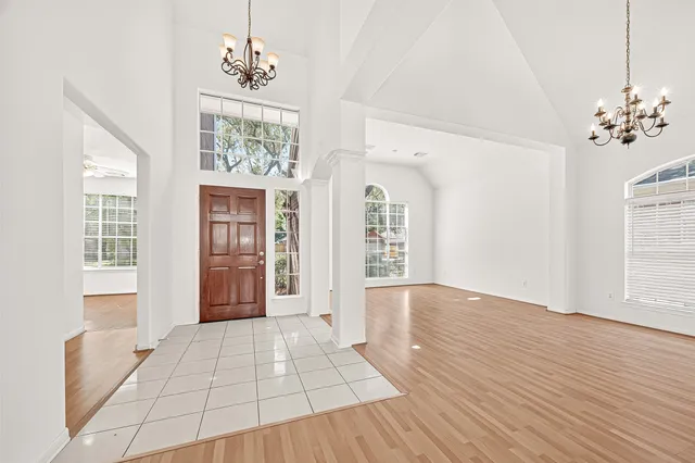 a view of an empty room with wooden floor fireplace and a window