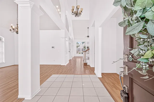 a view of an empty room with wooden floor and a kitchen