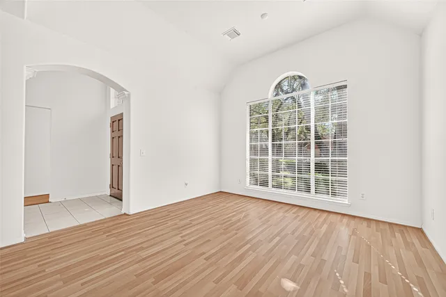 a view of an empty room with wooden floor and a fireplace
