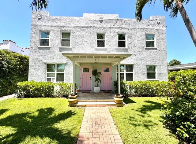 a view of a house with many windows plants and large tree