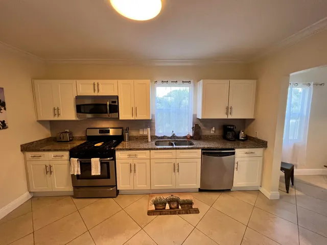 a kitchen with stainless steel appliances granite countertop a stove a sink and a microwave