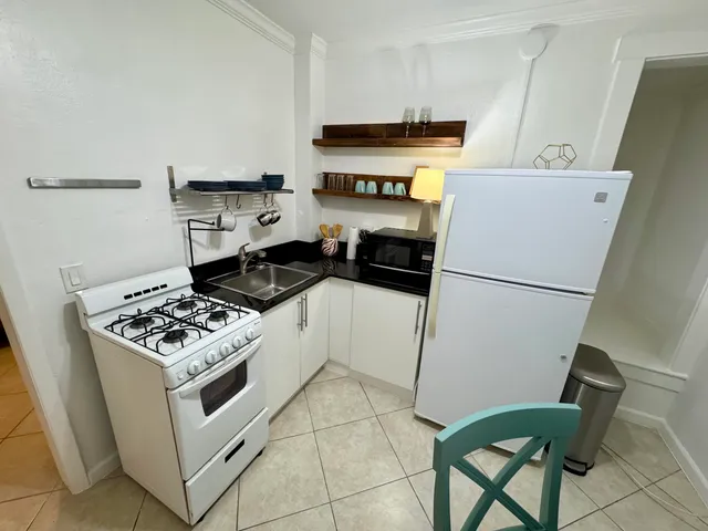 a kitchen with granite countertop a stove a refrigerator and a stove top oven