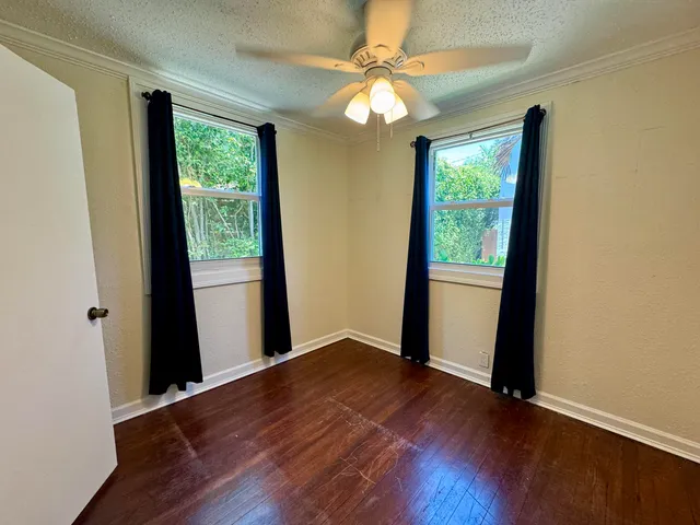 an empty room with wooden floor and windows