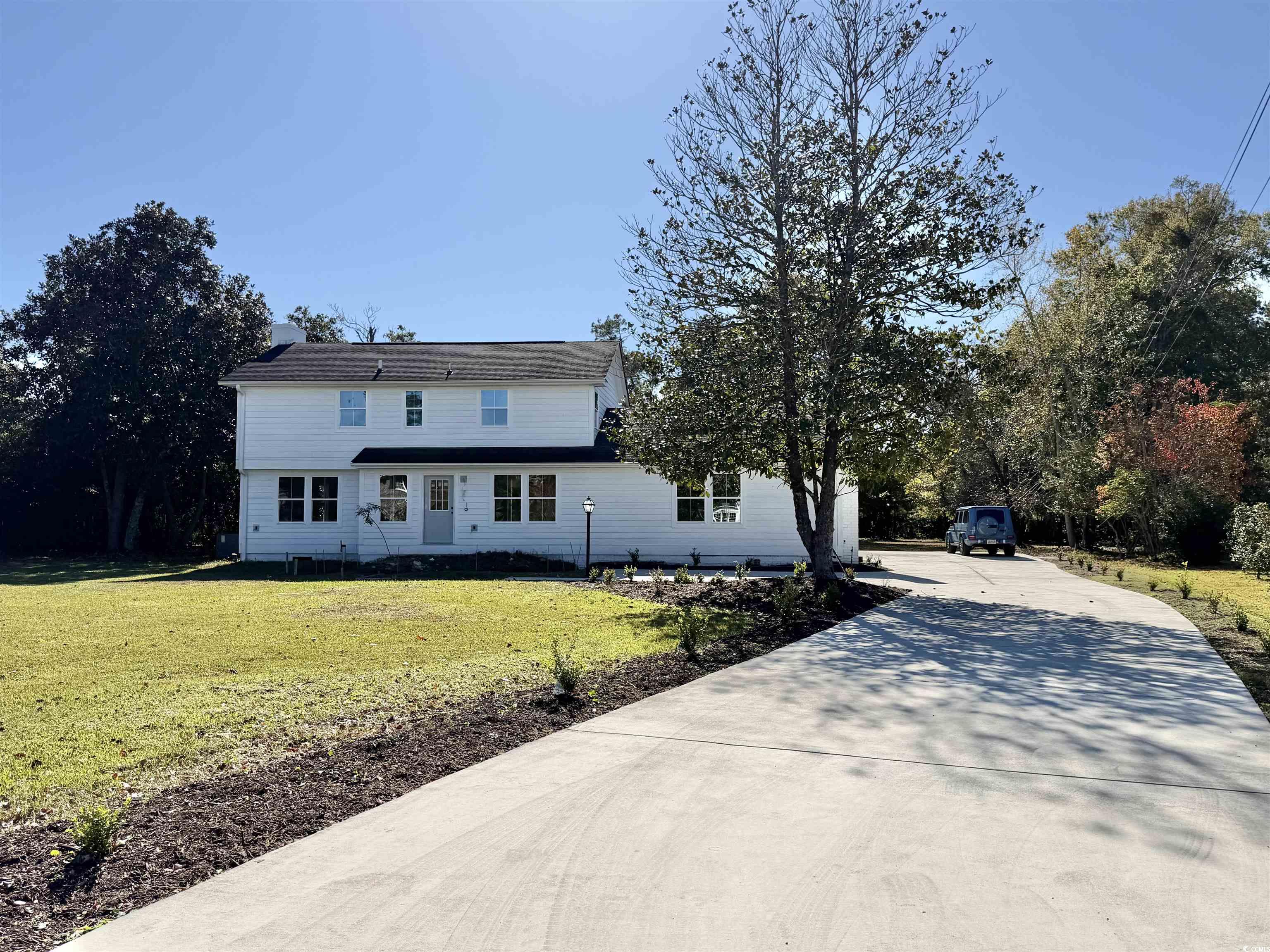 View of front of property featuring a front yard and concrete driveway